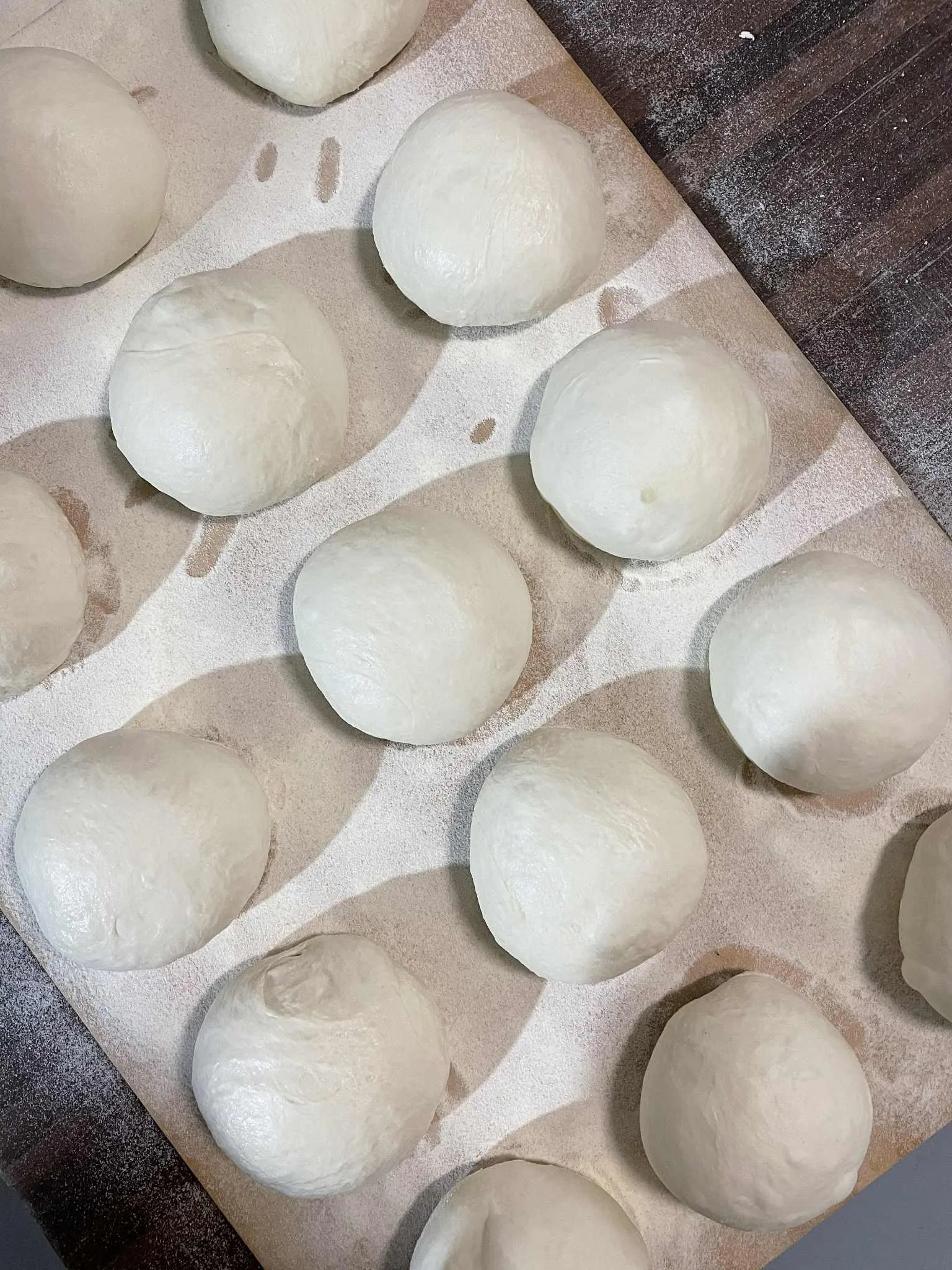 Fresh dough balls resting on a floured surface, ready for shaping